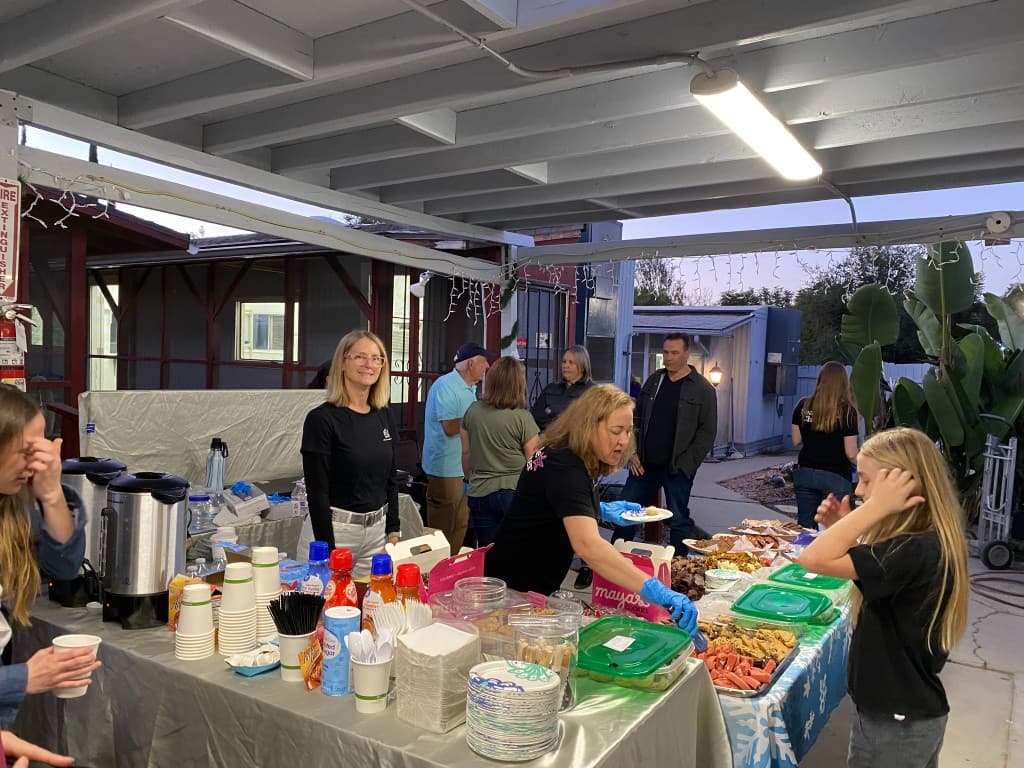 Staff and volunteer with a grey cat at an outdoor adoption event